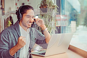 Man having web conversation looks at laptop, cheering, pumping fist