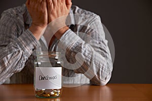 Man With Head In Hands Looking At Jar Labelled Christmas