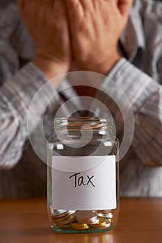 Man With Head In Hands Looking At Jar Labelled Tax