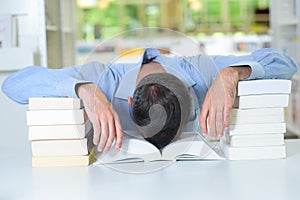 Man with head slumped in book photo