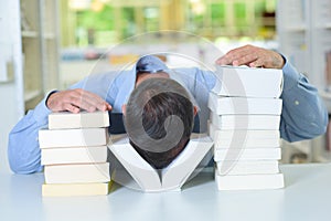 Man with head between two piles books