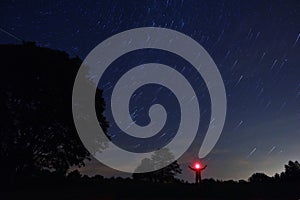 A man with a headlamp looks at the starry sky.