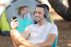 man in headphones at campsite on sunny day