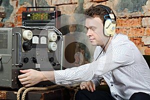 Man in headphones configures power source to radio receiver photo