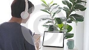 Man with headphones and digital tablet with blak screen on working table background for mock up, template