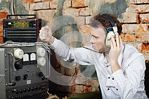 Man in headphones knocks on power source to radio receiver