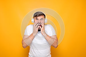 man with headphones listening to music grabbed his mouth and demonstrates horror