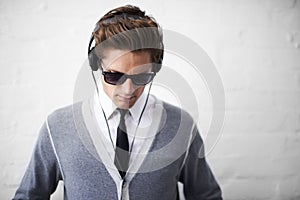 Man, headphones and listening to song and relaxing to music by wall background, sound and peace. Male person, meditation