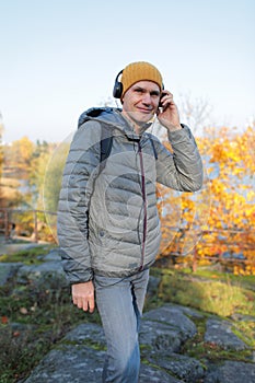 Man with headphones outdoors in a sunny autumn day