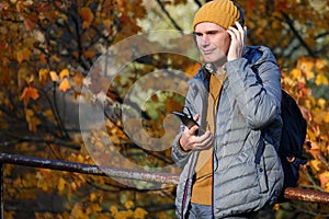 Man with headphones outdoors in a sunny autumn day