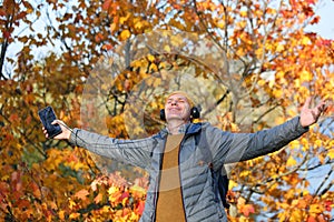 Man with headphones outdoors in a sunny autumn day