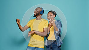 Man with headphones playing air guitar and woman showing rock sign