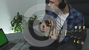 Man in headphones playing on electric guitar, close up view. Male music composer creating new lyric song. Close up view of guitar.