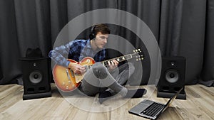 Man in headphones playing on guitar. Young guitarist performing the song on electric guitar and enjoying playing. Happy smiling