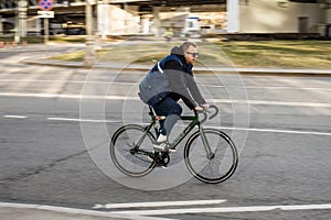 Man with headphones and sunglasses riding bicycle on city street