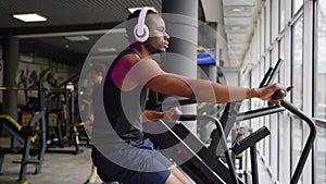 A man with headphones using exercise bike at the gym