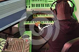 A man in headphones works in a recording studio with musical equipment on creating and composing music.