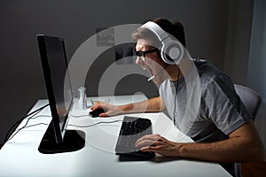 Man in headset playing computer video game at home