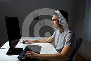 Man in headset playing computer video game at home