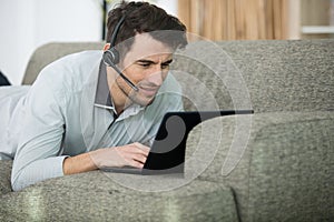 man with headset on sofa using laptop computer