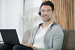man in headset working with laptop from home