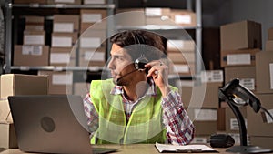 Man with headset working in on-site office of a warehouse discuss with customer