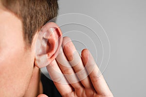 Man with hearing problem on grey background. Close up