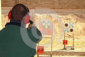Man with hearing protection shooting gun at pistol range
