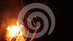Man heats hands at burning bonfire. Summer night. Camping