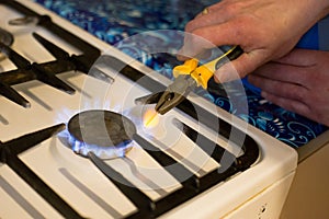 A man heats a nail over a gas stove fire to make a hole in a flower pot