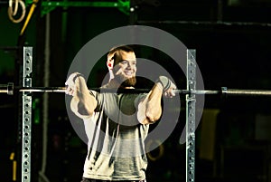 Man with heavyweight barbell in the dark gym