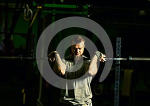 Man with heavyweight barbell in the dark gym