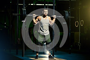 Man with heavyweight barbell in the dark gym