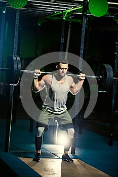 Man with heavyweight barbell in the dark gym