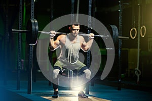 Man with heavyweight barbell in the dark gym