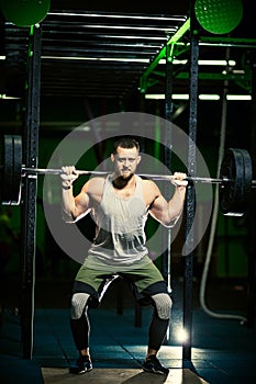 Man with heavyweight barbell in the dark gym