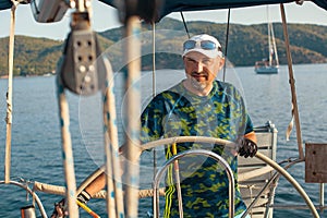 Man at helm leads a sailing yacht in the sea. Sport.