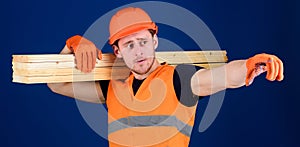 Man in helmet, hard hat and protective gloves pointing direction, blue background. Wooden materials concept. Carpenter