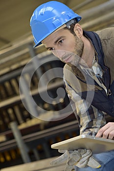 Man with helmet in manufacture using digital tablet