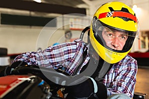 Man in helmet and other people driving car for karting