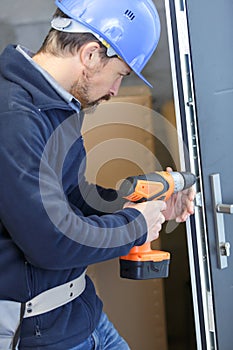 man in helmet perforating wall with drill in hands