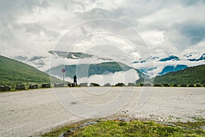 Man in helmet photographer taking photos back view of mountains landscape in rainy weather in Norway. Travel Lifestyle