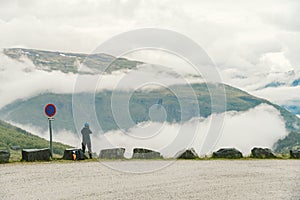 Man in helmet photographer taking photos back view of mountains landscape in rainy weather in Norway. Travel Lifestyle