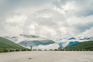 Man in helmet photographer taking photos back view of mountains landscape in rainy weather in Norway. Travel Lifestyle