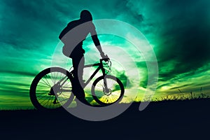 Man with helmet and protective gear on mountain bike against sunset sky photo