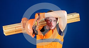 Man in helmet and protective gloves wiping sweat from forehead, blue background. Tired labourer concept. Carpenter