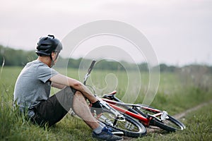Man in helmet rest at the roadside with bicycle