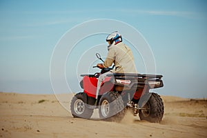 Man in helmet rides on atv in desert, action view