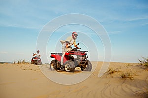 Man in helmet rides on atv in desert sands