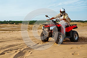 Man in helmet rides on atv in desert sands